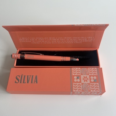 Caneta laranja em caixa laranja aberta com texto e padrões decorativos
