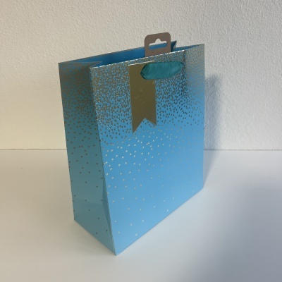 Saco de presente azul com alça de fita e etiqueta dourada