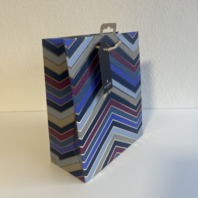 Saco de presente em papel com padrão geométrico azul e dourado