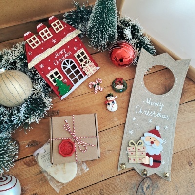 Decorações de Natal incluindo casinha vermelha, guirlanda, bolas, pequenas decorações, embalagem castanha e decoração de madeira com Pai Natal