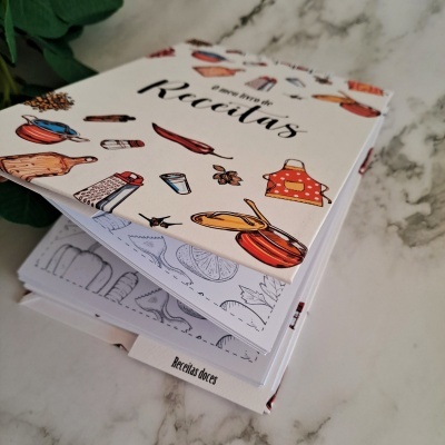 Livro de receitas com capas ilustradas coloridas sobre superfície marmoreada
