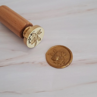 Selo de cera dourado com cabo de madeira e design gravado de limões e folhas