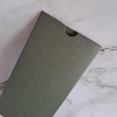 Envelope verde-acinzentado sobre superfície de mármore branco e cinzento