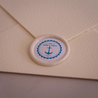 Envelope creme com selo redondo azul e branco com âncora e texto MADA & CHICO