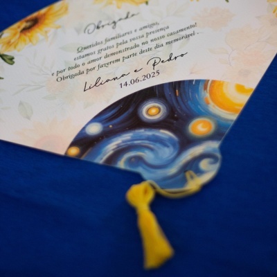 Convite de casamento com padrões florais amarelos e envelope azul com tassel amarelo