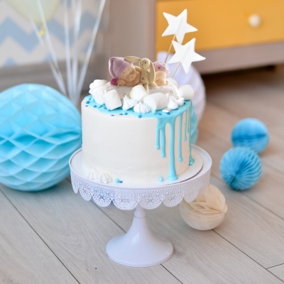 Bolo decorado branco com detalhes azuis e figuras de ursinhos e estrelas no topo