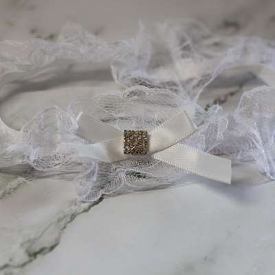 Liga de renda branca com laço de cetim e pedra brilhante
