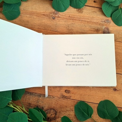 Livro aberto com texto e folhas verdes ao redor numa mesa de madeira