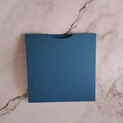 Envelope azul quadrado sobre fundo de mármore branco.