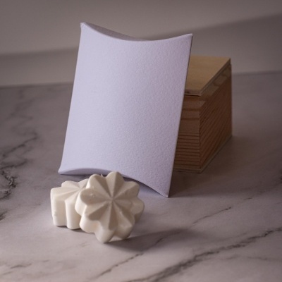 Sabonetes brancos em forma de flor com caixa de madeira e embalagem de papel branca sobre mármore cinzento