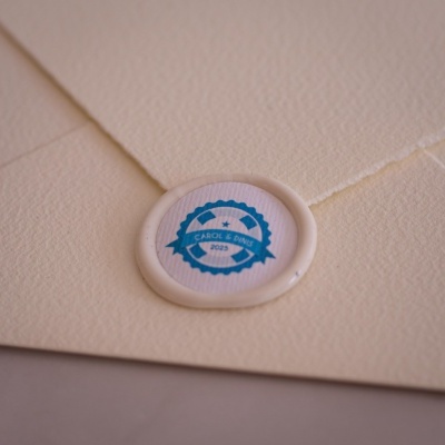Envelope creme com selo branco e etiqueta azul com texto