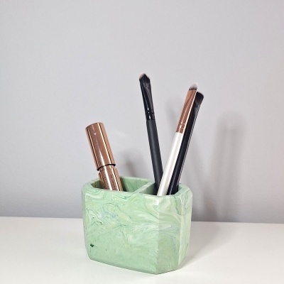 Suporte verde para maquilhagem com pincéis e baton