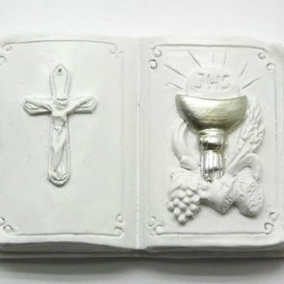 Escultura em relevo de livro aberto com crucifixo e cálice dourado