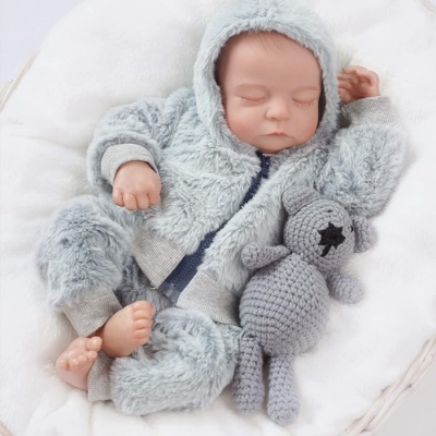 Boneco bebé realista com fato de pelúcia cinzento e ursinho de croché cinzento.