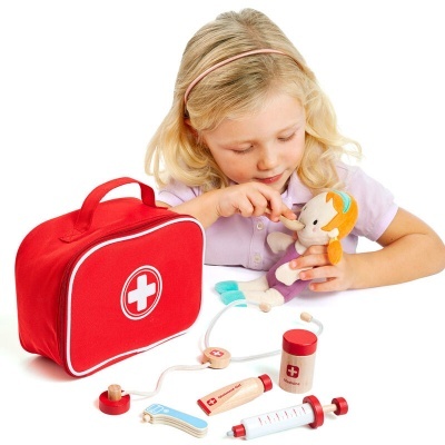 Menina a brincar com conjunto de brinquedo médico vermelho com cruz branca.