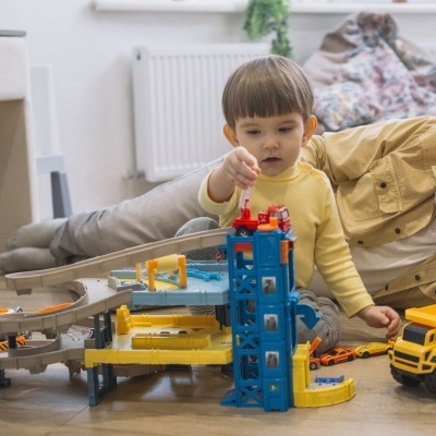 Criança a brincar com parque de estacionamento de brinquedo colorido no chão