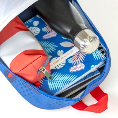 Interior da mochila azul com garrafa térmica preta, estojo vermelho e caderno com capa azul e folhas