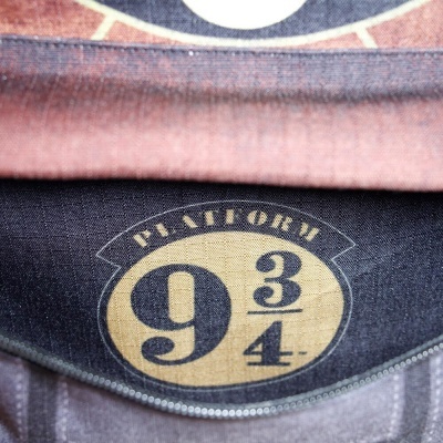 Símbolo da Plataforma 9 3/4 estampado em tecido preto com zíper cinza e tecido vermelho