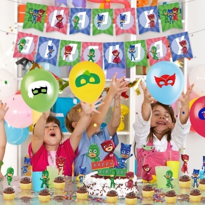 Crianças celebrando aniversário com decoração temática PJ Masks e bolo com toppers dos personagens