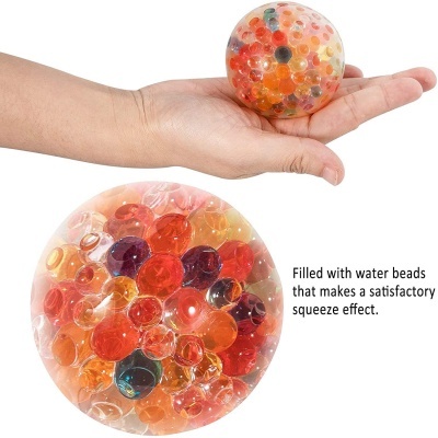 Bola transparente cheia de esferas de gel coloridas numa mão sobre fundo branco