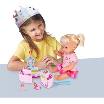 Menina a brincar com brinquedo de bolo de aniversário e boneca vestida de rosa