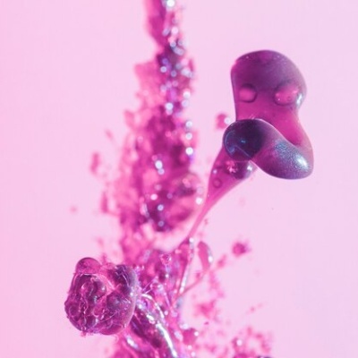 Gotas e salpicos de líquido cor-de-rosa num fundo rosa claro