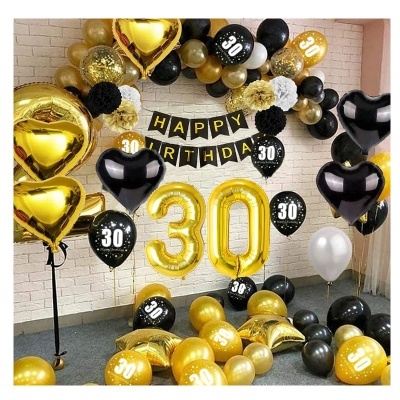 Decoração de festa com balões dourados, pretos e brancos e faixa 'HAPPY BIRTHDAY'.