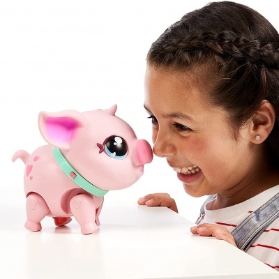 Brinquedo porquinho rosa interagindo com menina sorridente sobre mesa branca