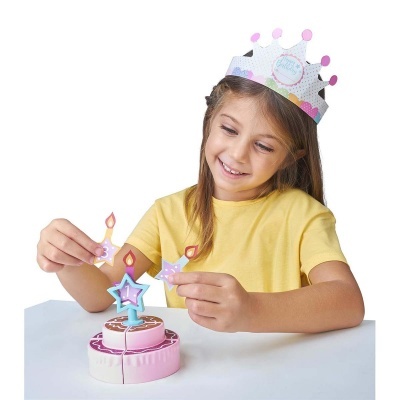 Criança com coroa de papel a brincar com bolo de brinquedo e velas