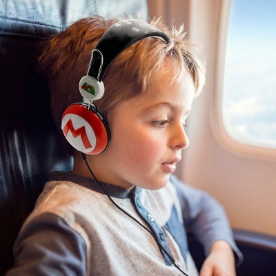 Criança com auscultadores vermelhos e brancos numa poltrona de avião