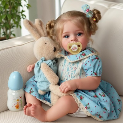 Boneca realista com vestido azul e chupeta amarela sentada num sofá com coelho de peluche e biberão ao lado