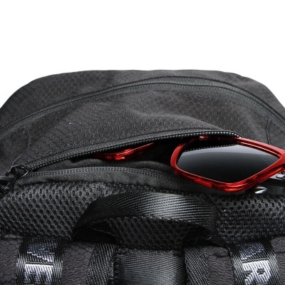 Mochila preta com bolso aberto e óculos de sol vermelhos