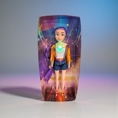 Boneca com cabelo roxo e roupa colorida numa caixa translúcida com luz verde no peito