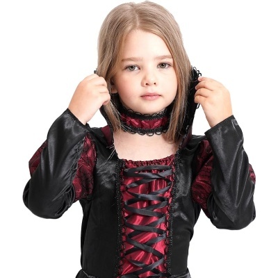 Criança com vestido gótico preto e vermelho com rendas e laços.