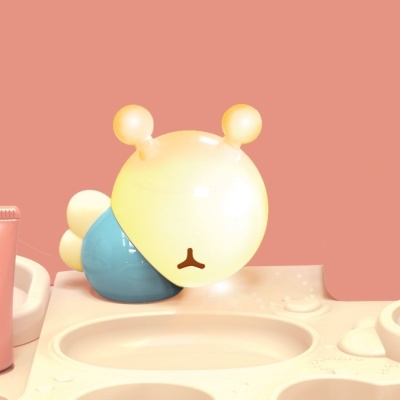 Figura decorativa lagarta amarela e azul em superfície bege