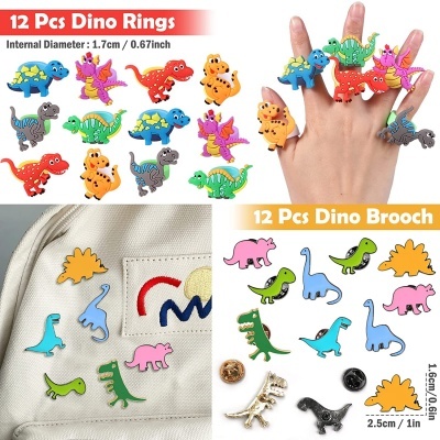 Anéis e broches coloridos de dinossauros exibidos em mão e em tecido.