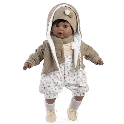 Boneca vestida com casaco bege, gorro, cachecol, camisa com bolinhas e calças com padrão floral.