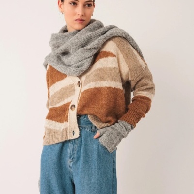 Mulher com casaco às riscas castanhas e bege, jeans azuis, cachecol e luvas cinzentas