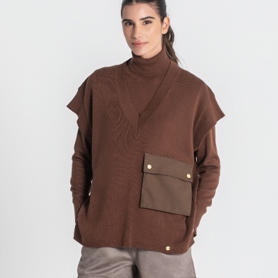 Mulher a usar camisola castanha e colete com bolso frontal e calções cinzentos