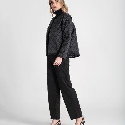 Mulher com casaco preto acolchoado, calças pretas e sapatos de salto