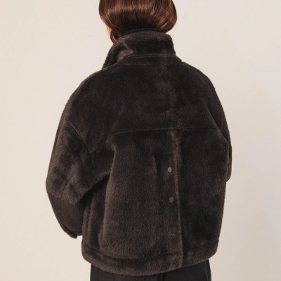 Casaco felpudo castanho escuro visto de costas com gola alta e calças pretas