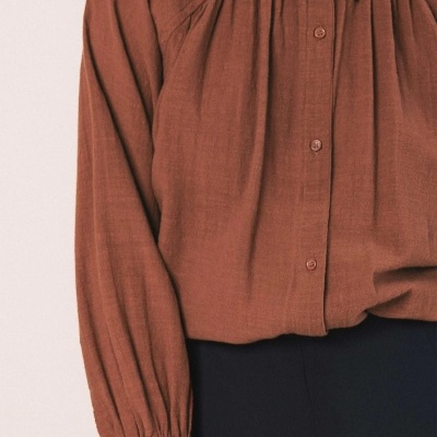 Camisa castanha com botões e punhos, combinada com calças pretas