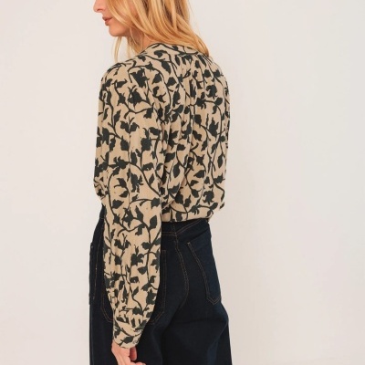 Blusa feminina bege com padrão floral preto, mangas compridas e gola redonda, vista de lado