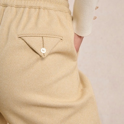 Calças bege padrão espinha de peixe com bolso traseiro com botão e camisola creme com botões dourados no pulso