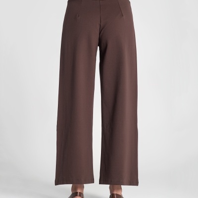 Calças largas castanhas vistas de costas com sandálias