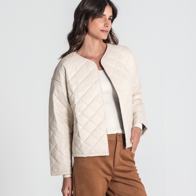 Mulher a usar casaco curto acolchoado bege com padrão quadriculado.