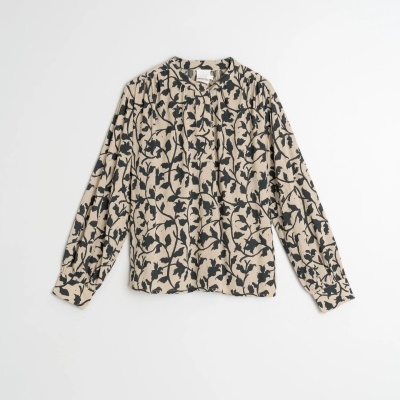Blusa feminina bege com padrão de folhas pretas, manga comprida, botão na gola