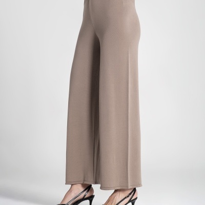 Calças largas bege com cintura elástica e botão dourado, usadas com sapatos pretos de salto