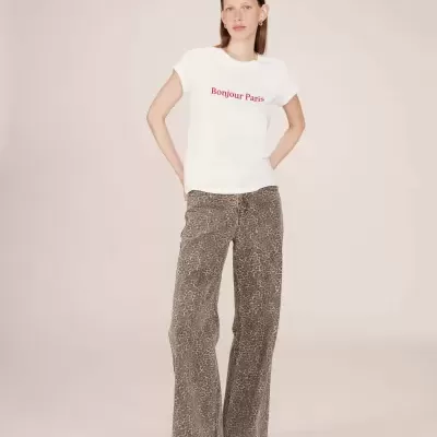 Mulher com camiseta branca 'Bonjour Paris' e jeans animal print castanho.