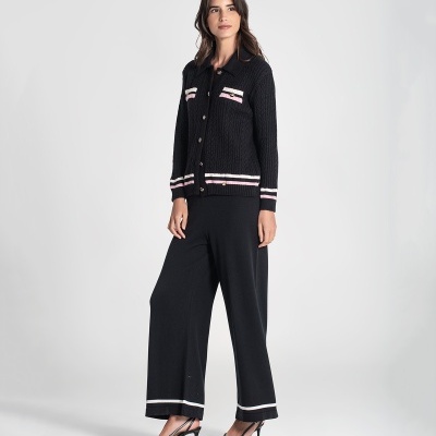 Mulher com casaco e calças pretas de malha e sapatos pretos